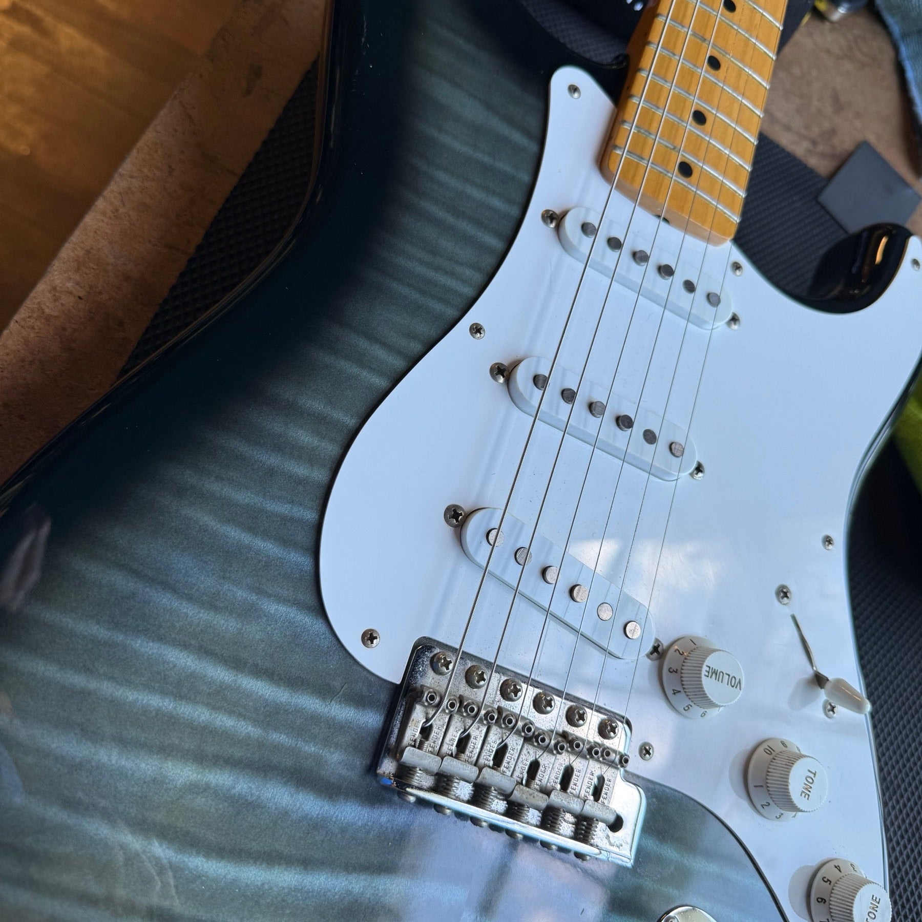 Japanese Fender Stratocaster with a blue-green burst flame top and maple neck on the repair bench