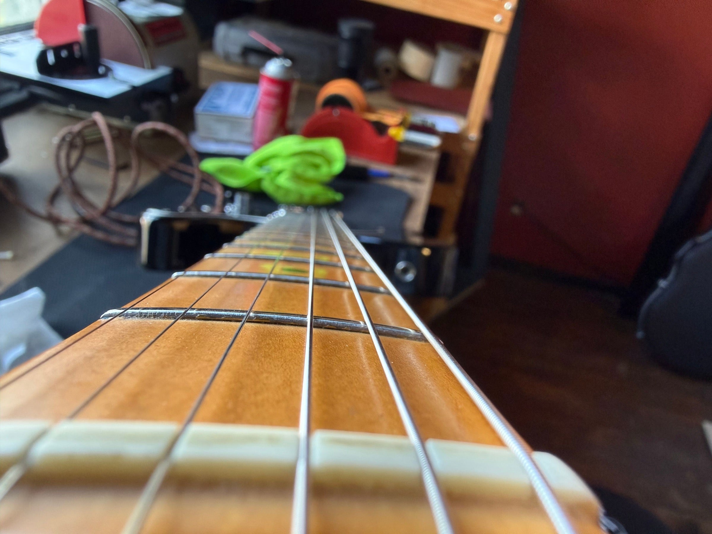 Sighting down the freshly leveled and polished frets of a maple-neck Fender Telecaster on the repair bench