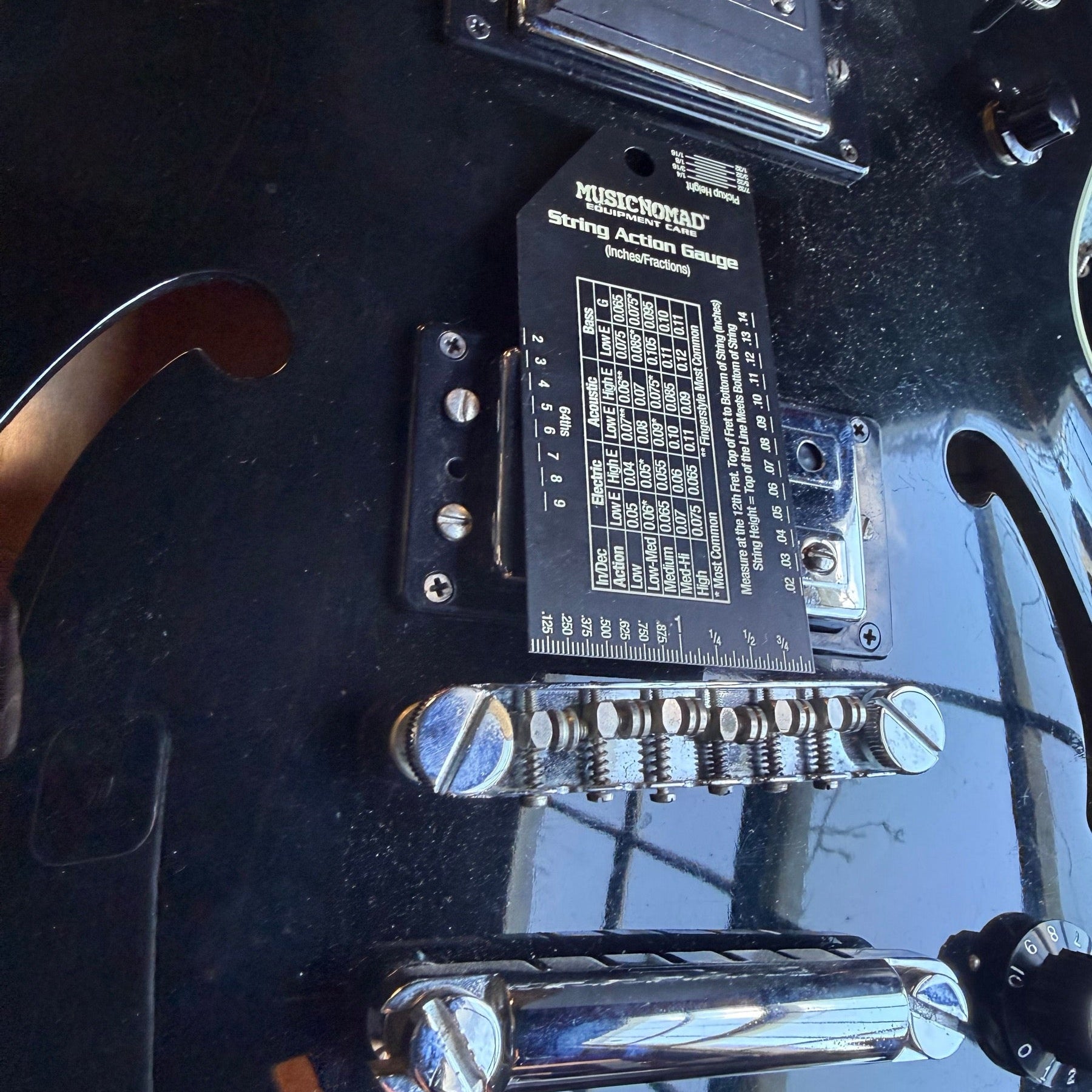 Black Guild Starfire hollowbody on the repair bench with a string action gauge resting on the top