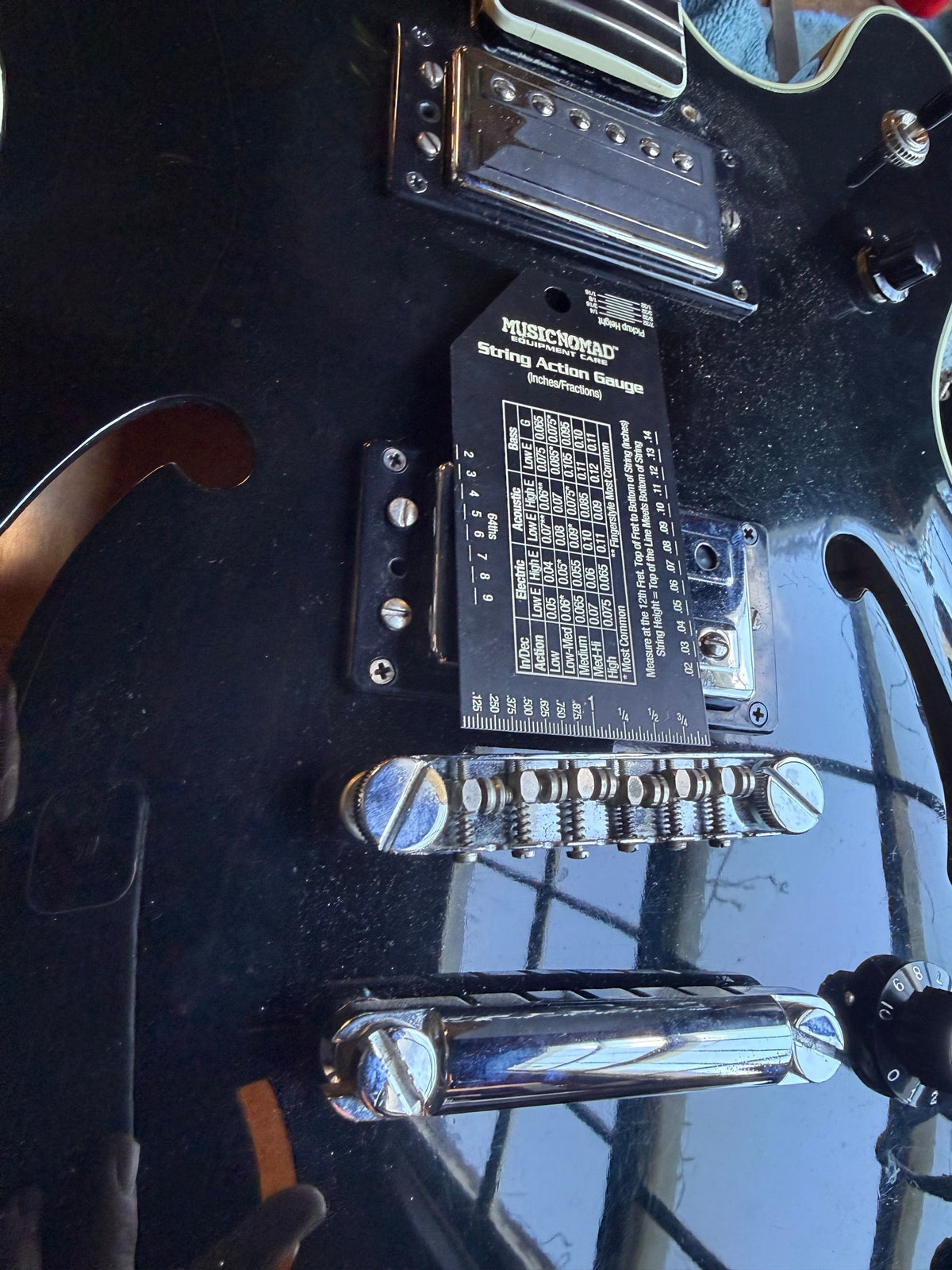 Black Guild Starfire hollowbody on the repair bench with a string action gauge resting on the top