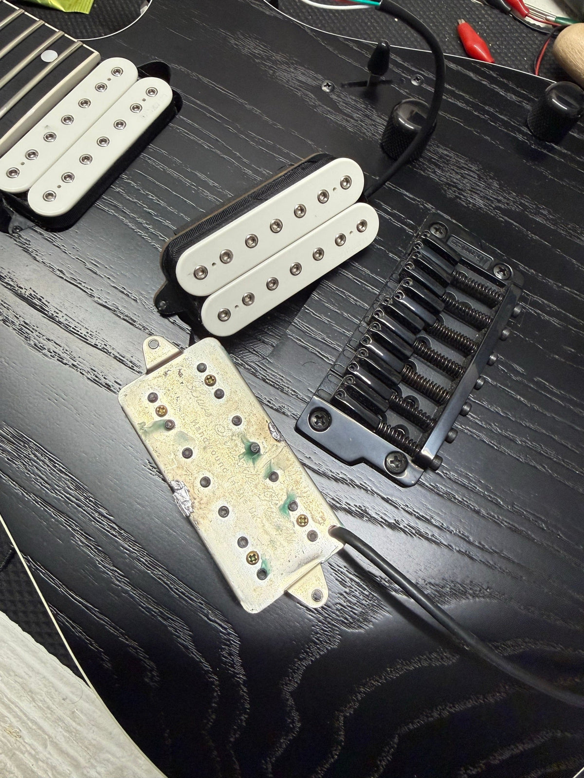 Ibanez seven-string electric on the repair bench for a bridge pickup swap