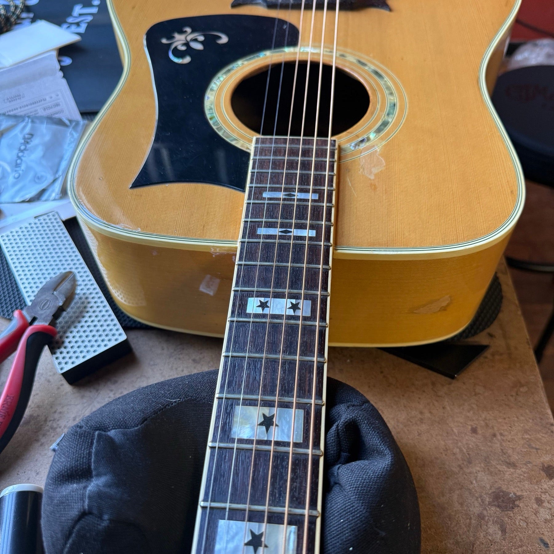 Vintage natural-finish Ibanez dreadnought with star inlays and an ornate pickguard on the repair bench