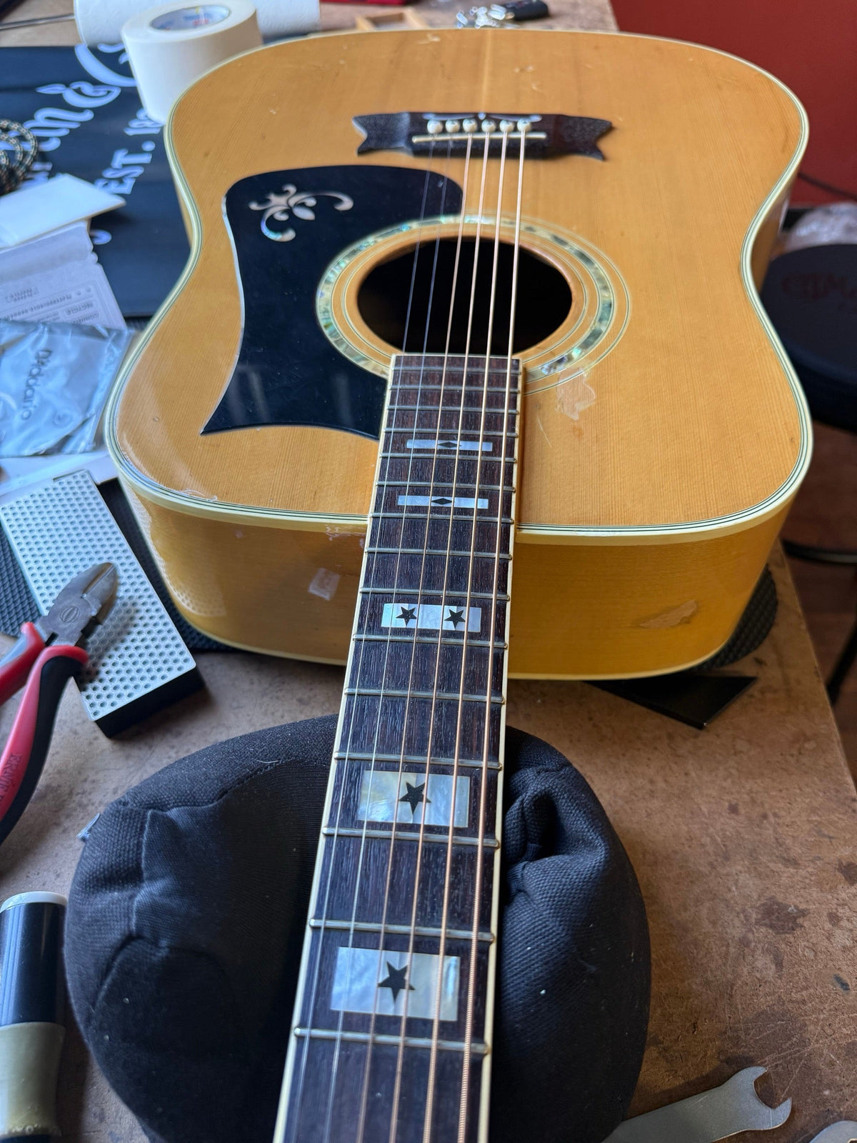 Vintage natural-finish Ibanez dreadnought with star inlays and an ornate pickguard on the repair bench