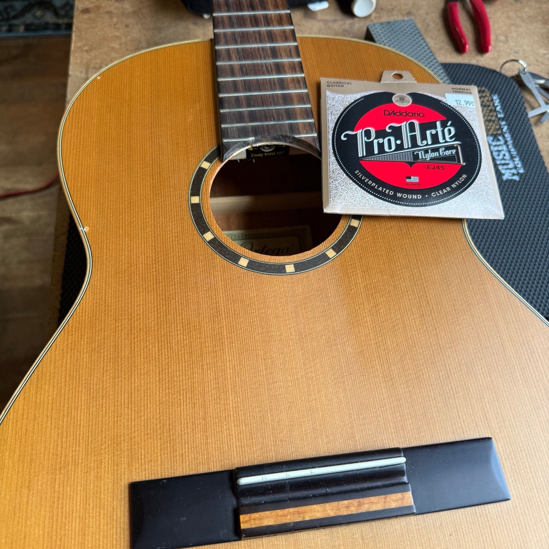 Ortega classical guitar on the repair bench with a set of D'Addario Pro-Arte nylon strings resting on the top