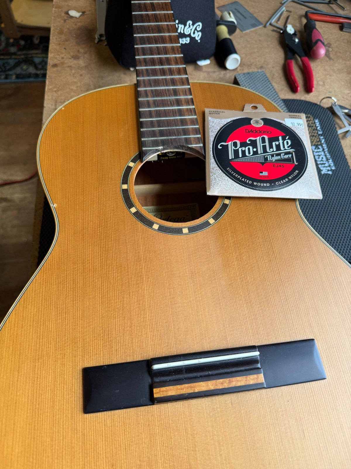 Ortega classical guitar on the repair bench with a set of D'Addario Pro-Arte nylon strings resting on the top