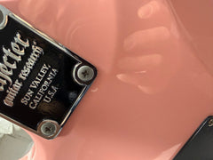 Neck plate of a pink Schecter electric guitar on the repair bench