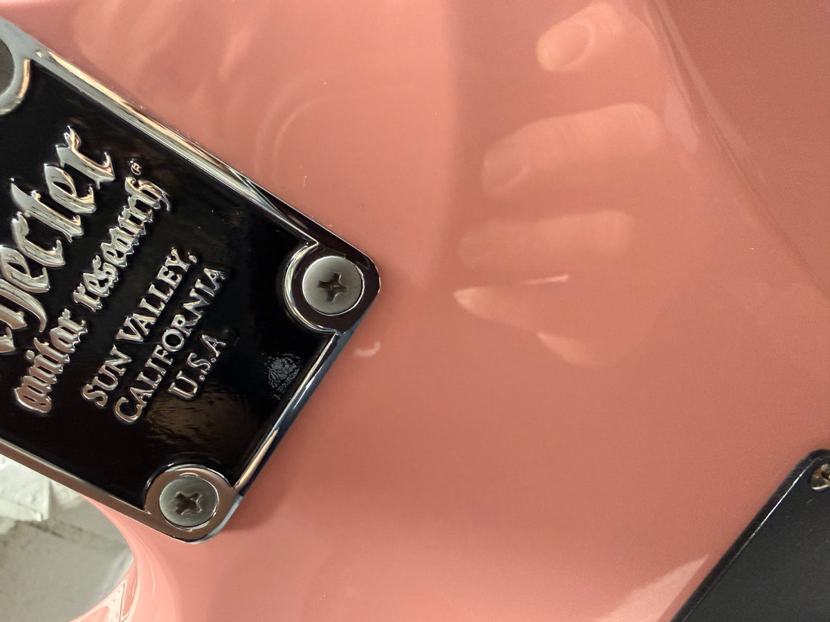 Neck plate of a pink Schecter electric guitar on the repair bench
