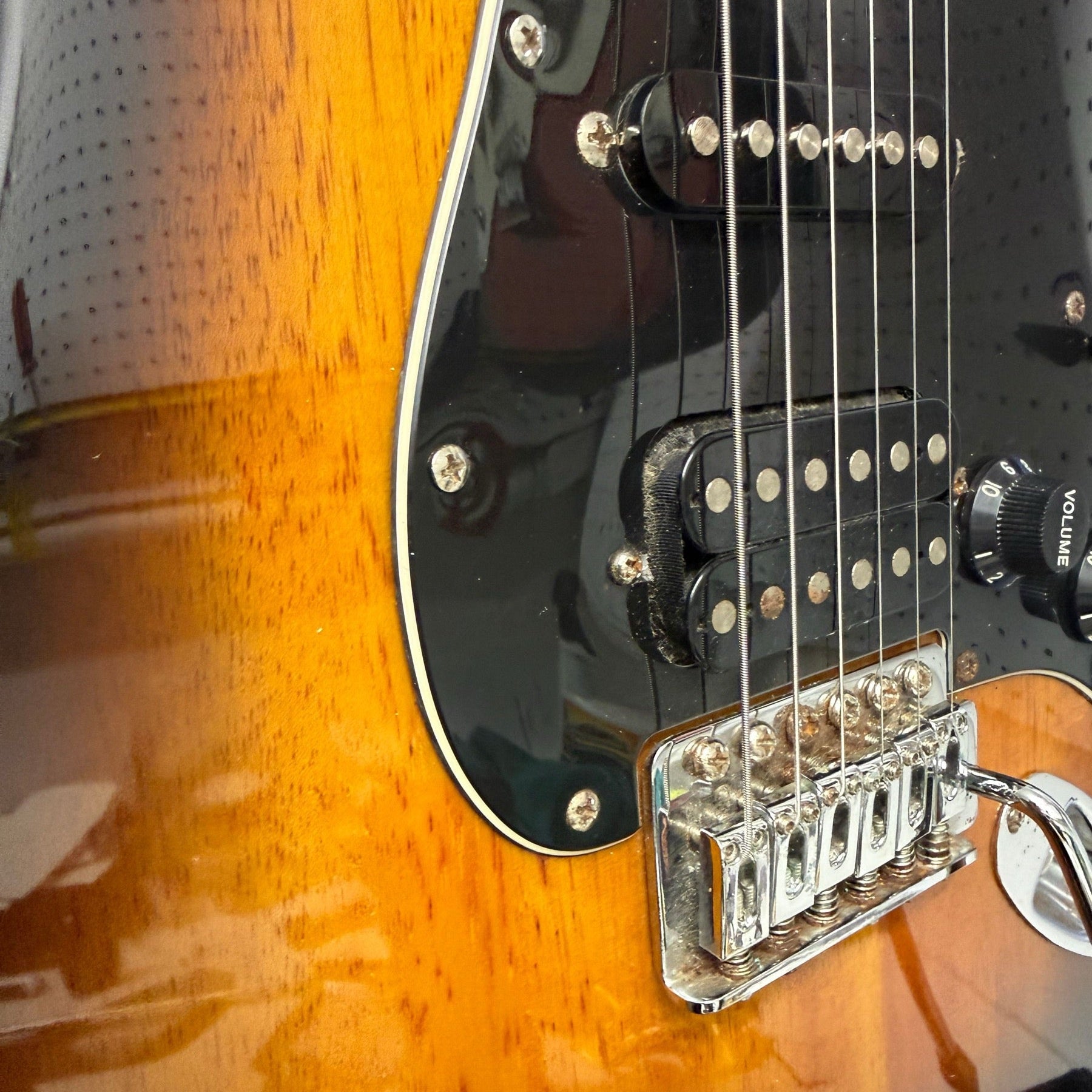 Sunburst Squier Stratocaster with a black pickguard on the repair bench after cleaning and setup