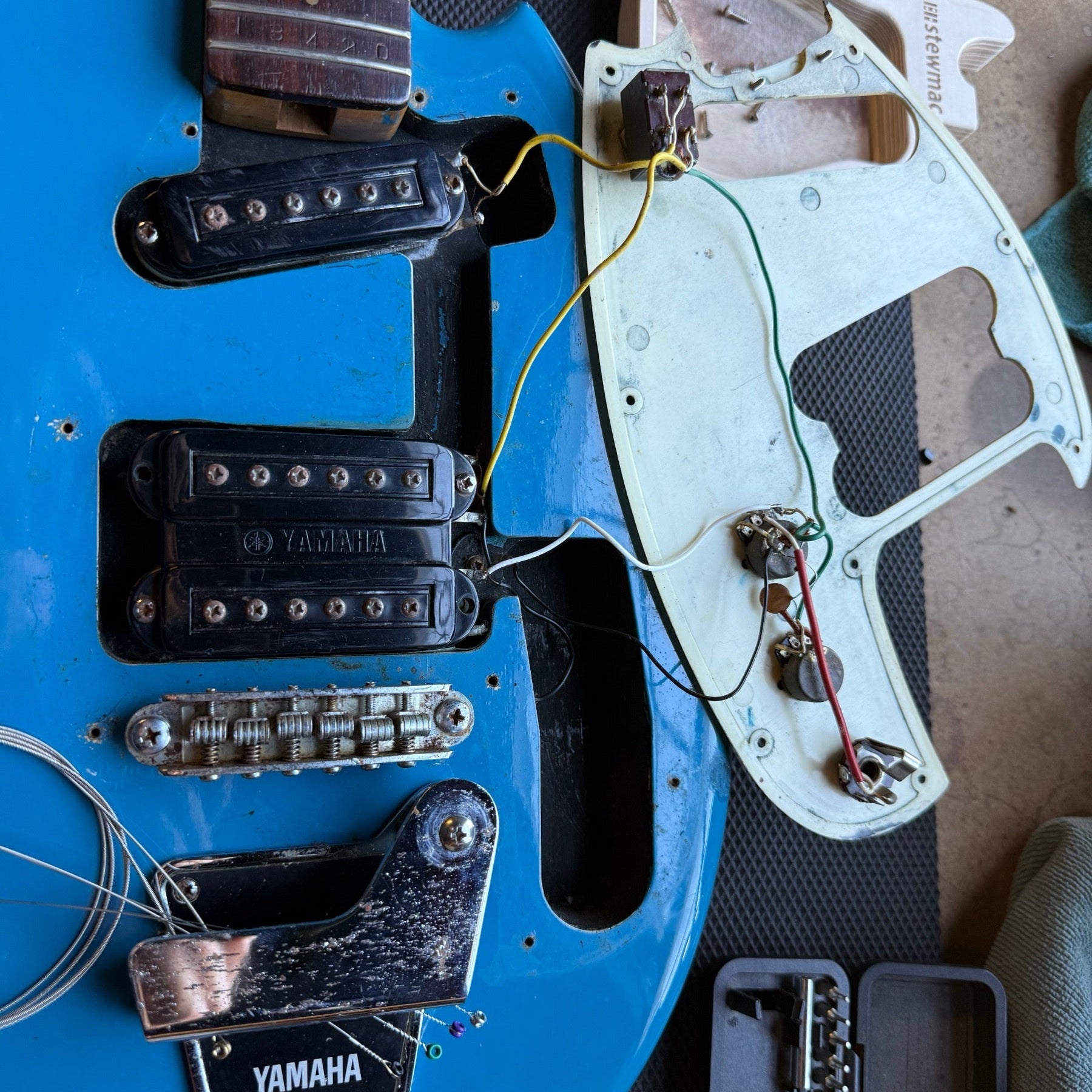 Blue vintage Yamaha electric guitar on the repair bench with the neck off and the pickguard wiring exposed