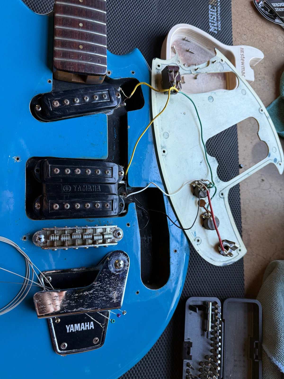 Blue vintage Yamaha electric guitar on the repair bench with the neck off and the pickguard wiring exposed