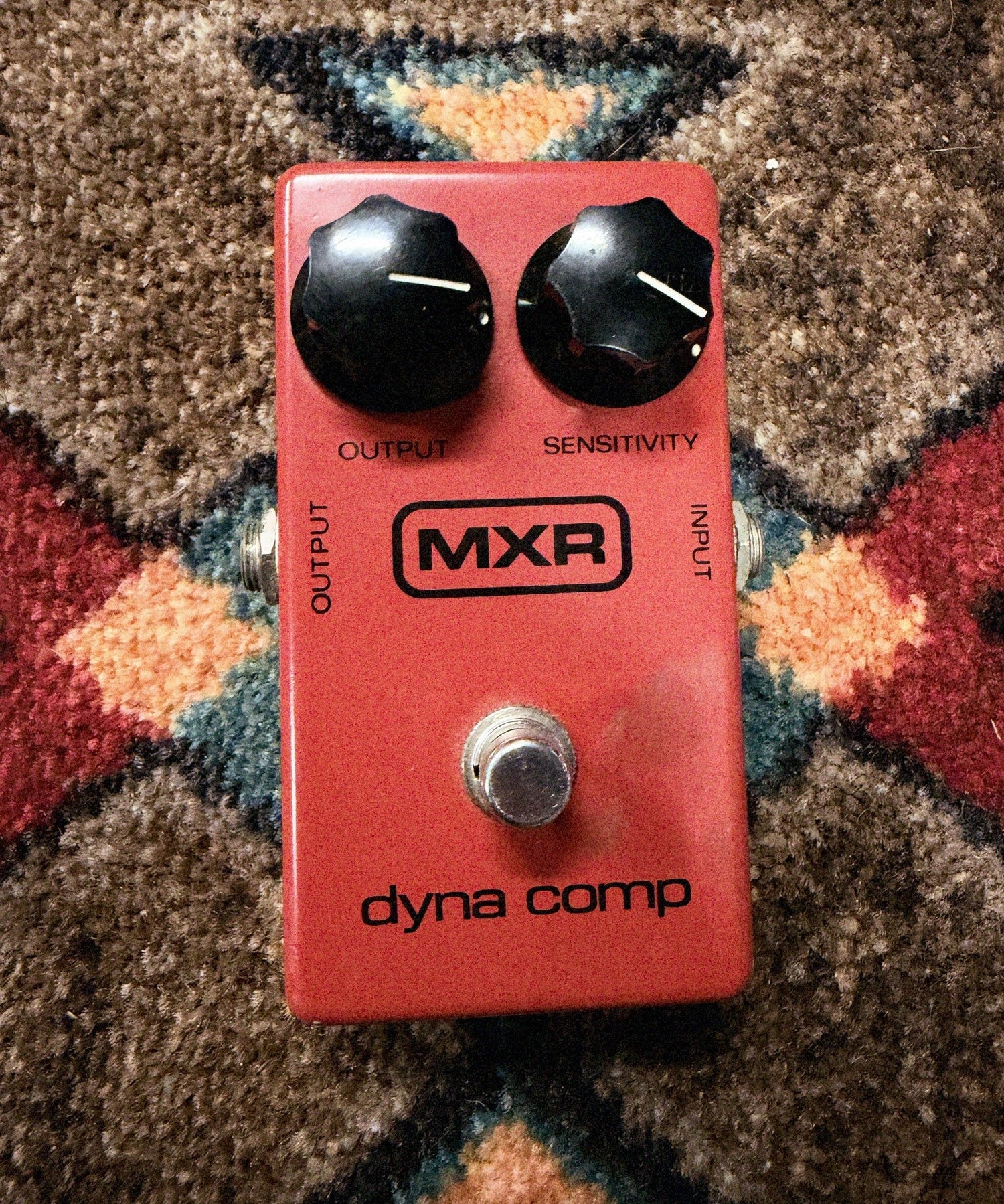 1975-1984 MXR MX-102 Block Logo Dyna Comp, red: top with the Output and Sensitivity knobs, the block MXR logo, dyna comp and the footswitch, no LED