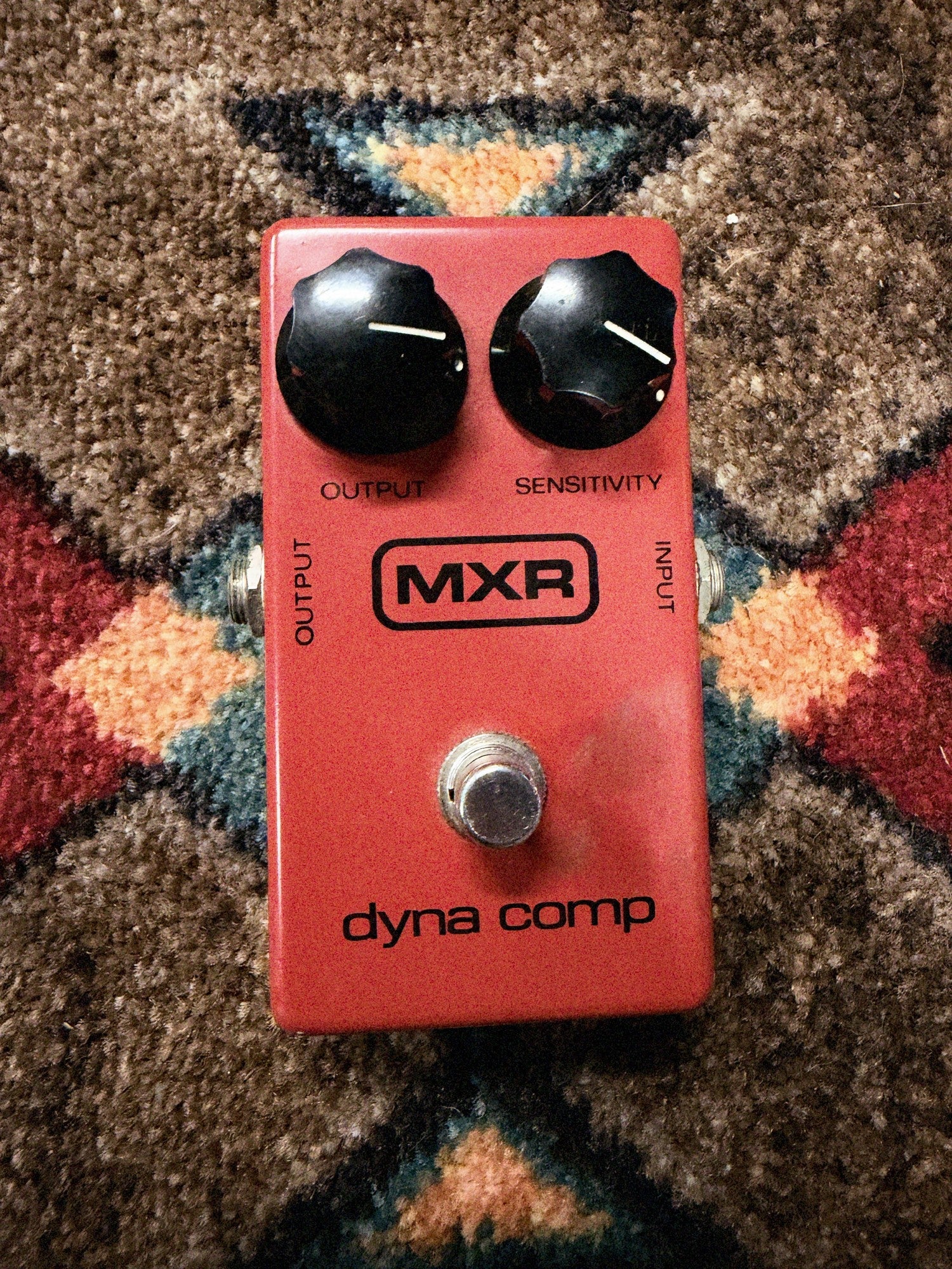 1975-1984 MXR MX-102 Block Logo Dyna Comp, red: top with the Output and Sensitivity knobs, the block MXR logo, dyna comp and the footswitch, no LED