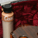 Oasis OH-14 humidifier clipped over the edge of a red velvet lined case beside a guitar body