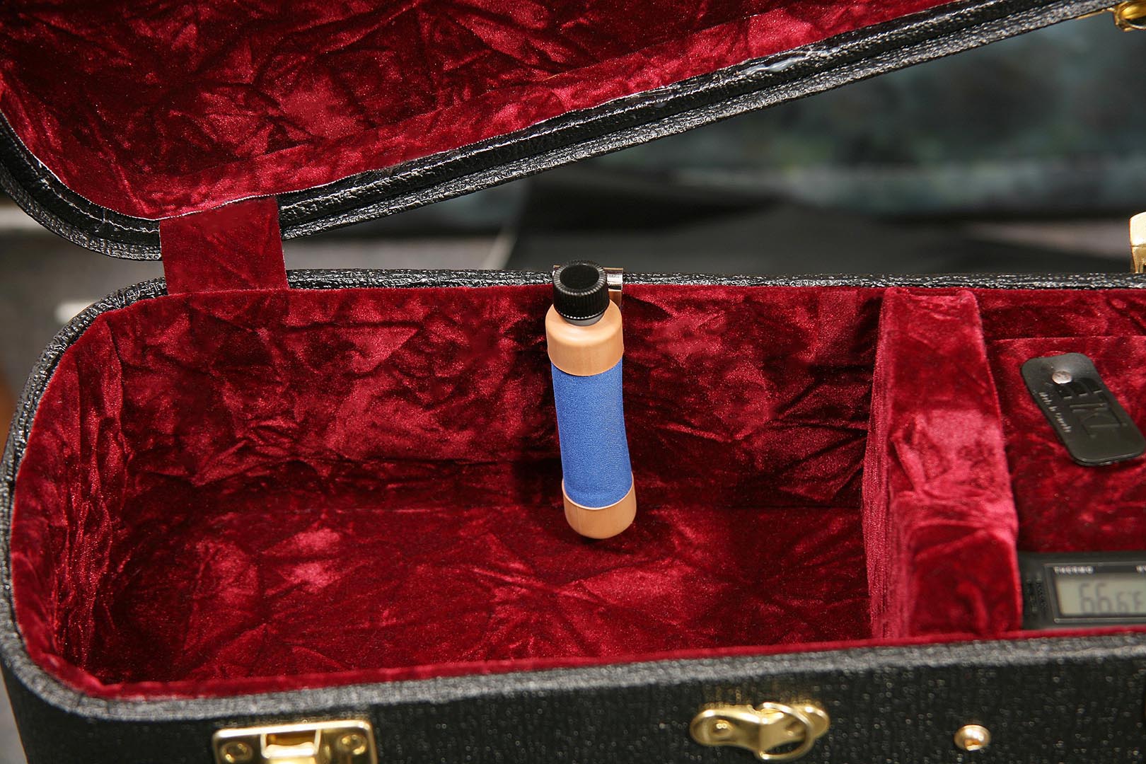 Oasis OH-6 humidifier standing in the accessory compartment of an open red velvet lined guitar case