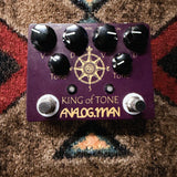 Analogman King of Tone V4, purple: top with the Volume, Drive and Tone knobs for each side, two footswitches and the gold compass graphic