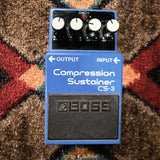 Boss CS-3 Compression Sustainer, blue: top with the Level, Tone, Attack and Sustain knobs, the check light and the footswitch