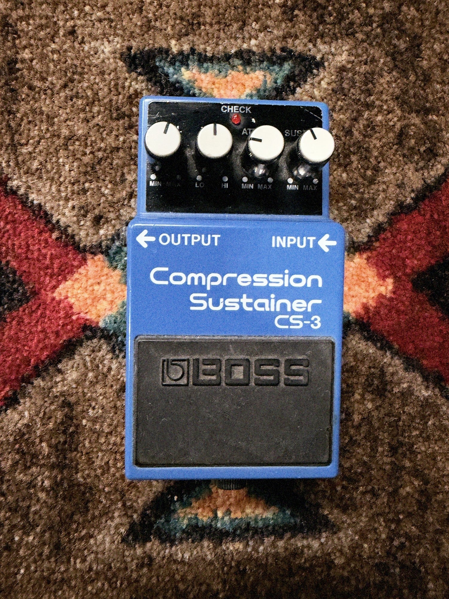 Boss CS-3 Compression Sustainer, blue: top with the Level, Tone, Attack and Sustain knobs, the check light and the footswitch
