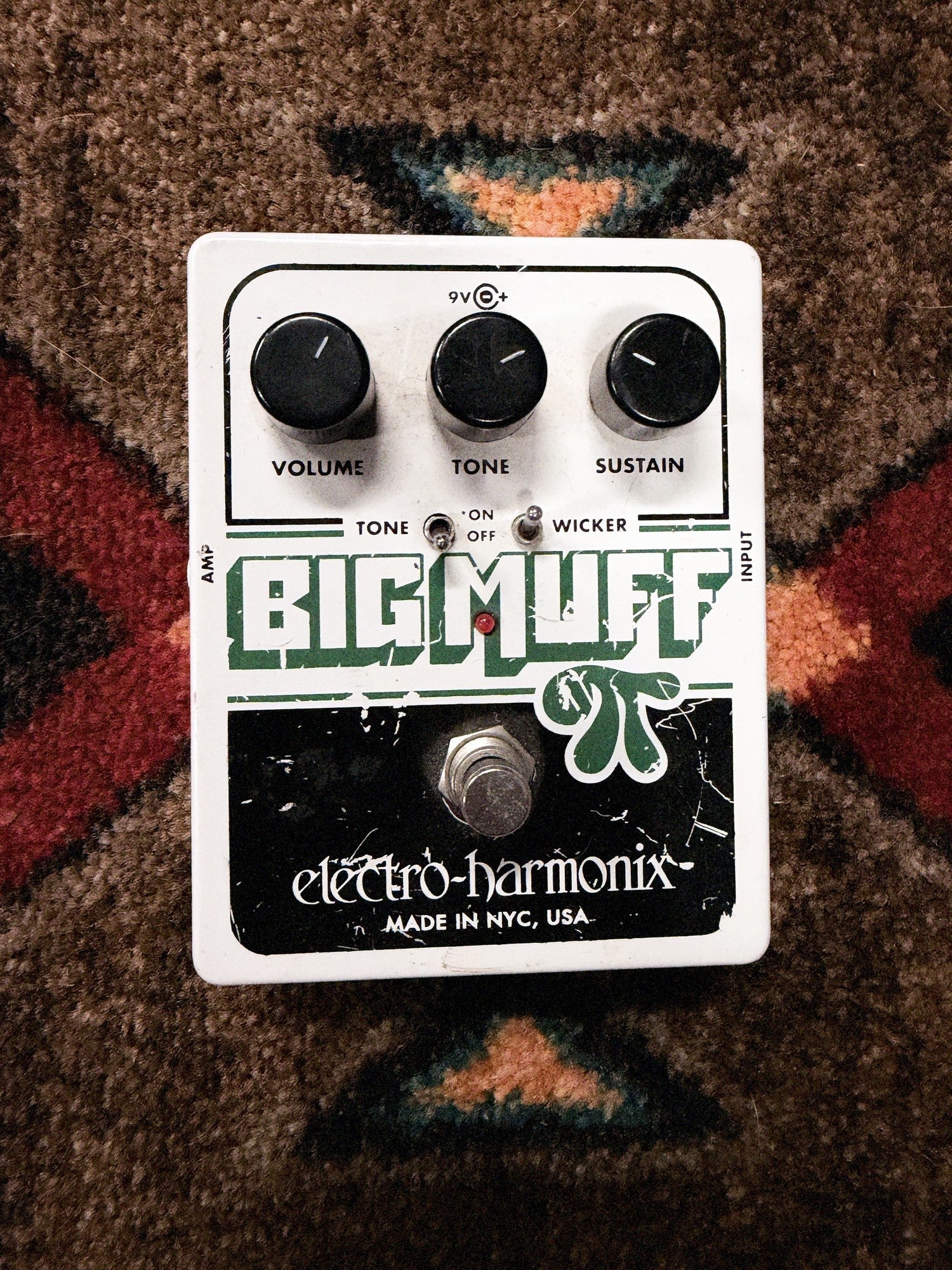 Electro-Harmonix Big Muff Pi with Tone Wicker, white: top with the Volume, Tone and Sustain knobs, the Tone and Wicker switches and the footswitch, with scratches and chips in the green and black print