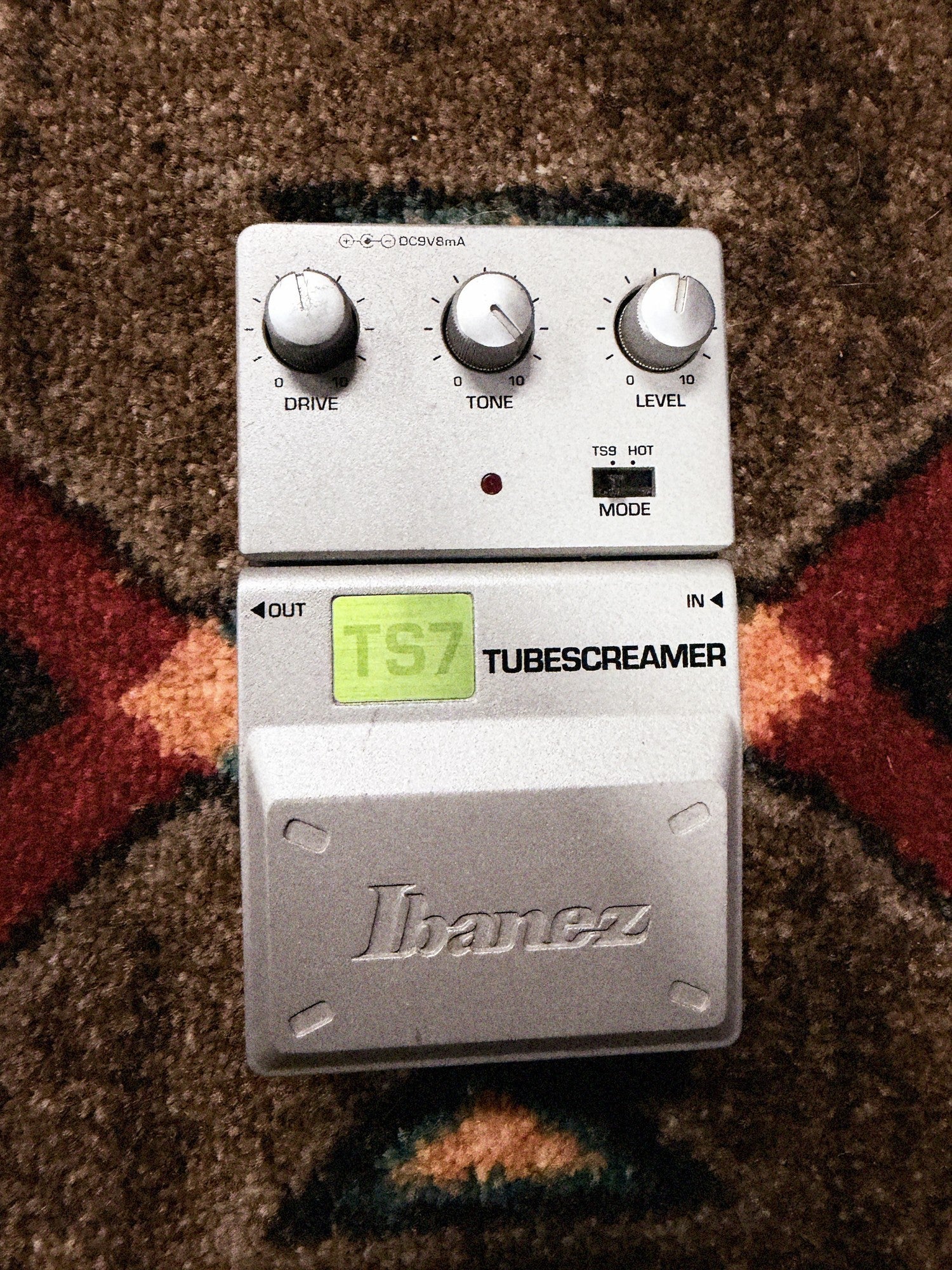 Ibanez TS7 Tube Screamer, silver: top with the Drive, Tone and Level knobs, the TS9 and Hot mode switch, the LED, the green TS7 label and the Ibanez pedal