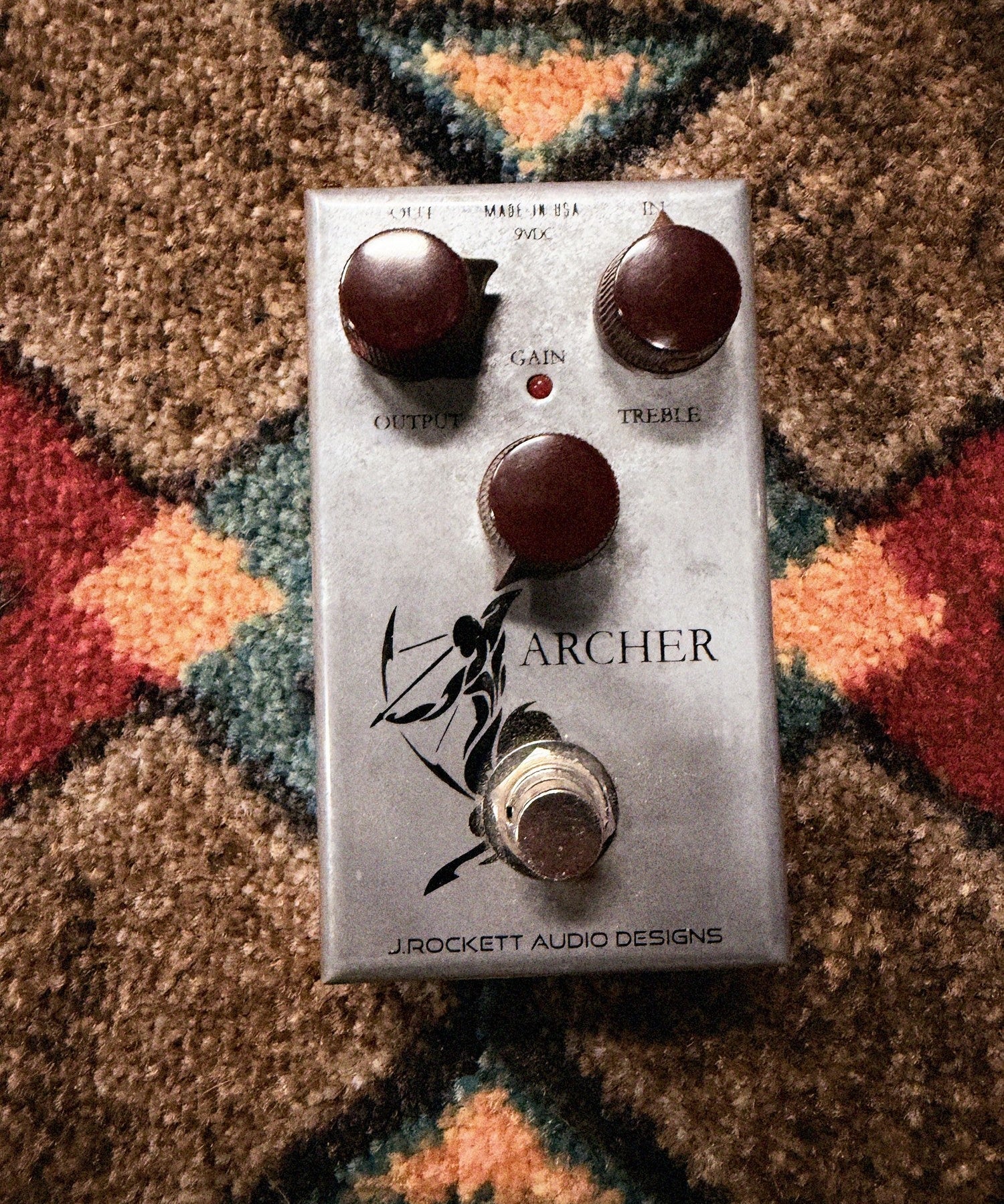 J. Rockett Audio Designs Archer, silver: top with the Output, Gain and Treble knobs, the LED, the archer drawing and the footswitch