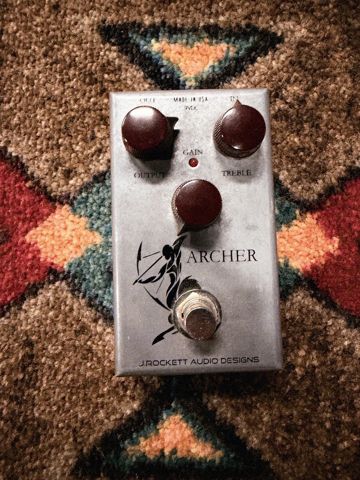 J. Rockett Audio Designs Archer, silver: top with the Output, Gain and Treble knobs, the LED, the archer drawing and the footswitch