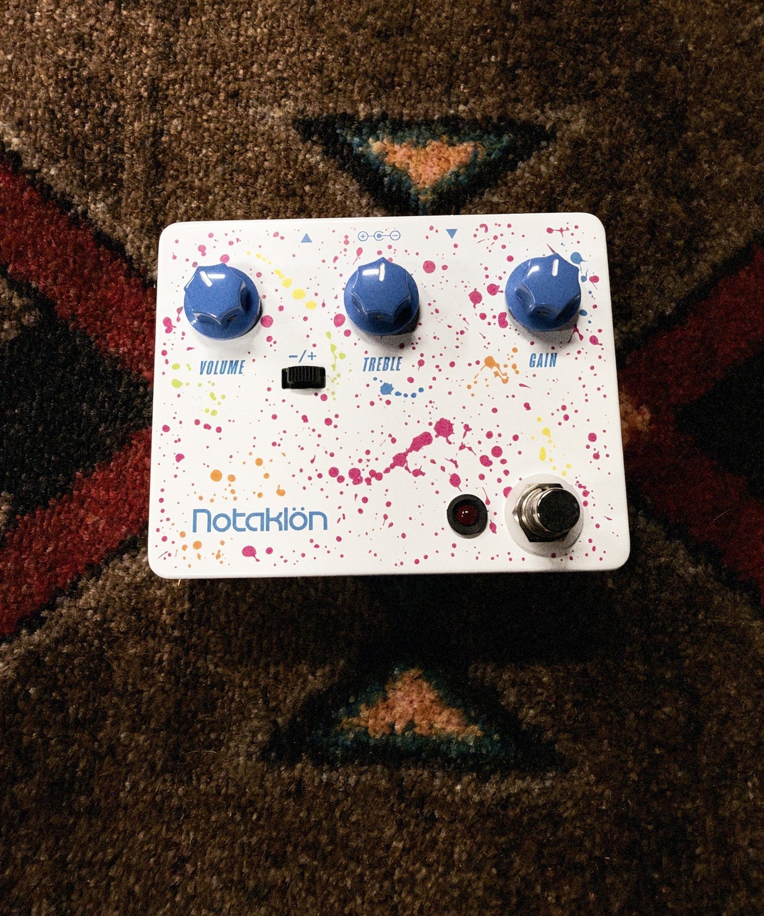 JHS Notaklön, white: top with the Volume, Treble and Gain knobs, the −/+ switch and the paint splatter graphic