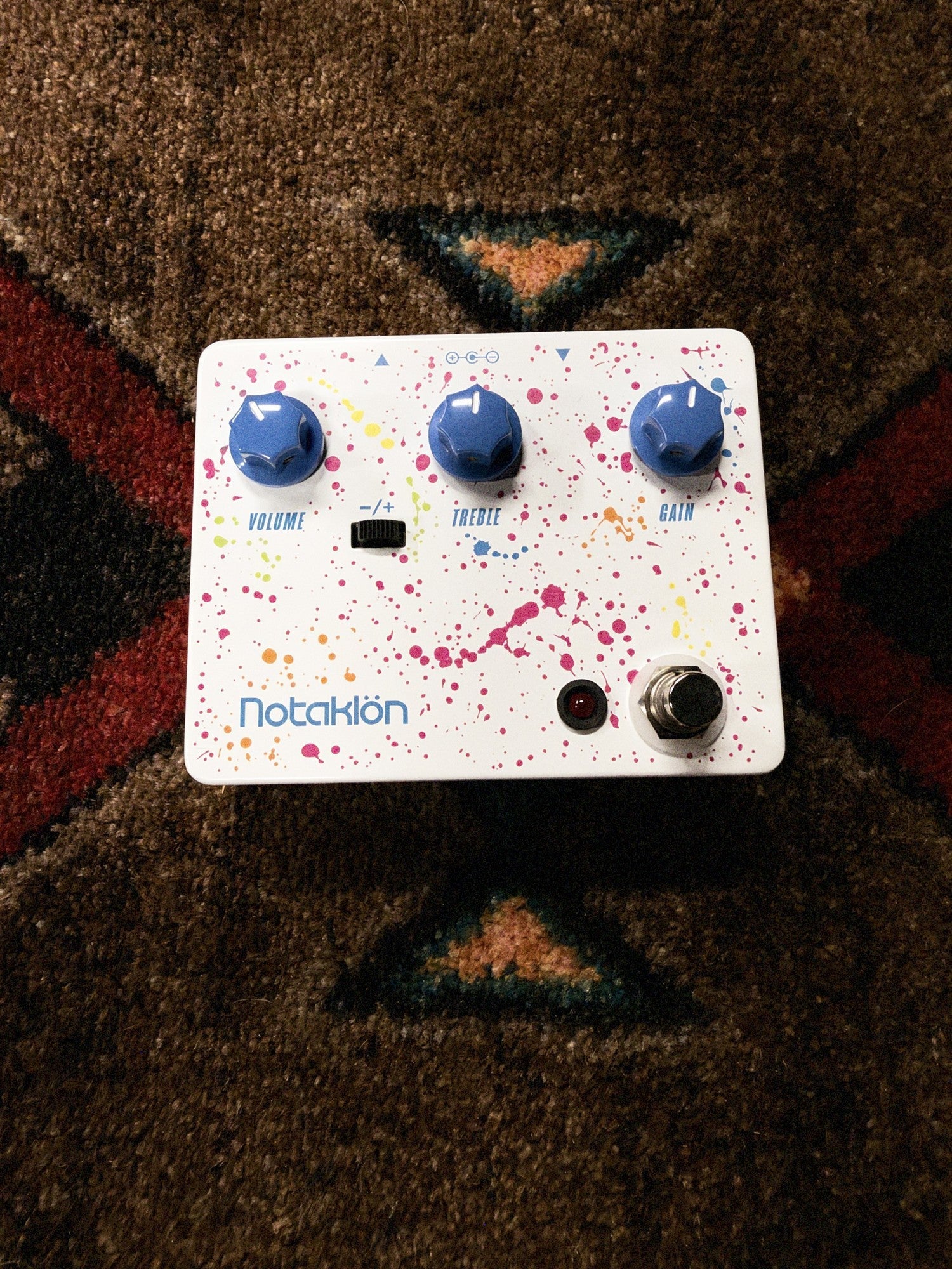 JHS Notaklön, white: top with the Volume, Treble and Gain knobs, the −/+ switch and the paint splatter graphic