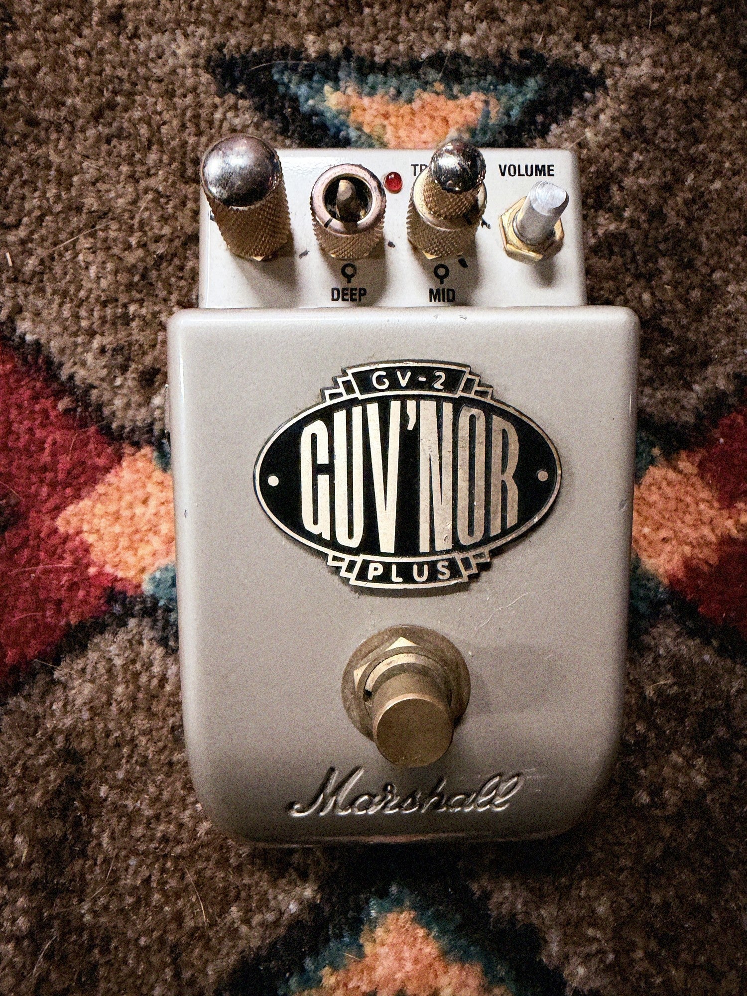 Marshall GV-2 Guv'nor Plus, silver: top with the Gain knob, the Deep and Mid rings, the Treble knob, the bare Bass and Volume shafts, the badge and the footswitch