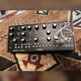 Moog Mother-32, black: the panel from above with white patch cables in the patch bay and wood end cheeks