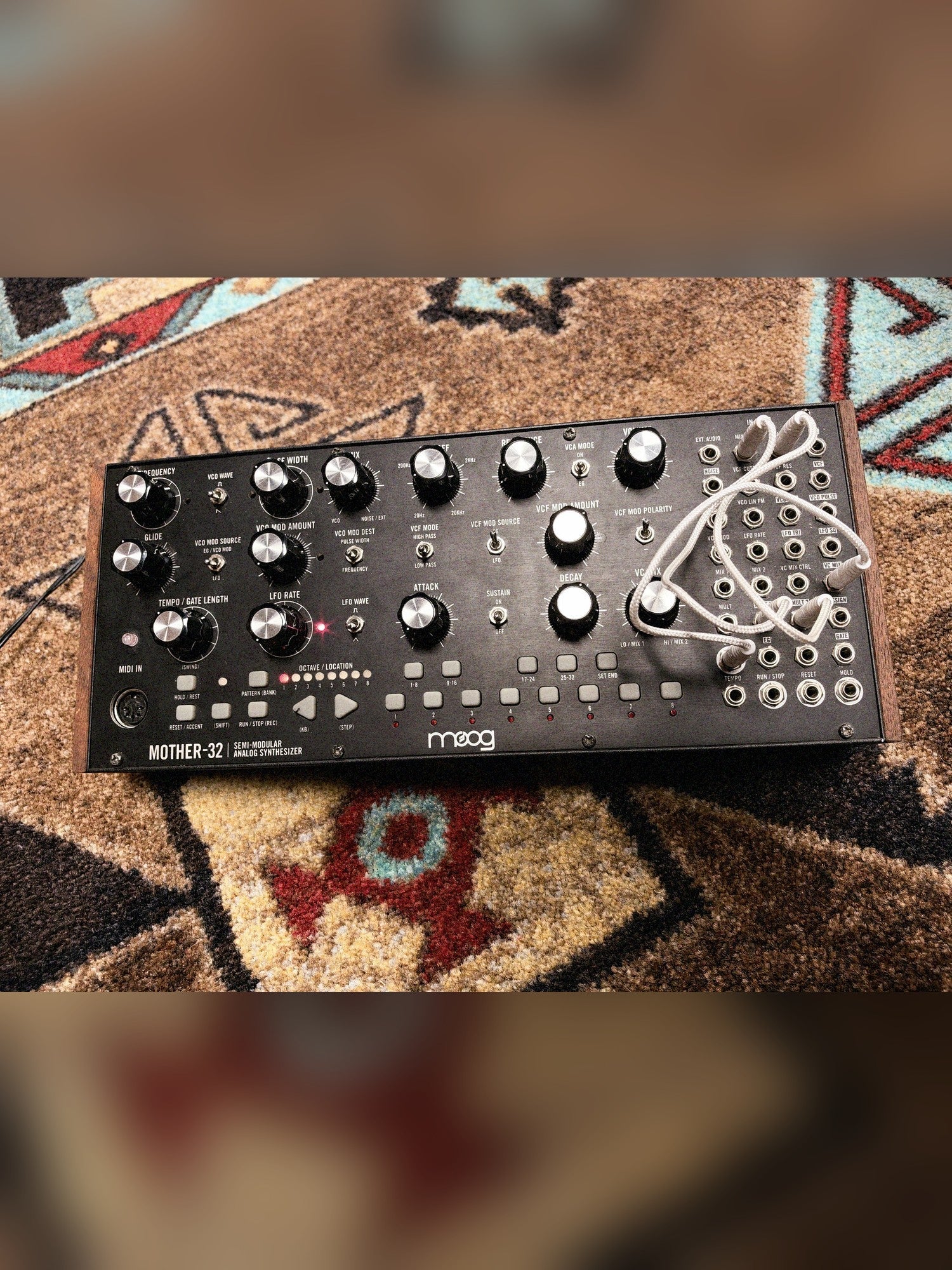 Moog Mother-32, black: the panel from above with white patch cables in the patch bay and wood end cheeks