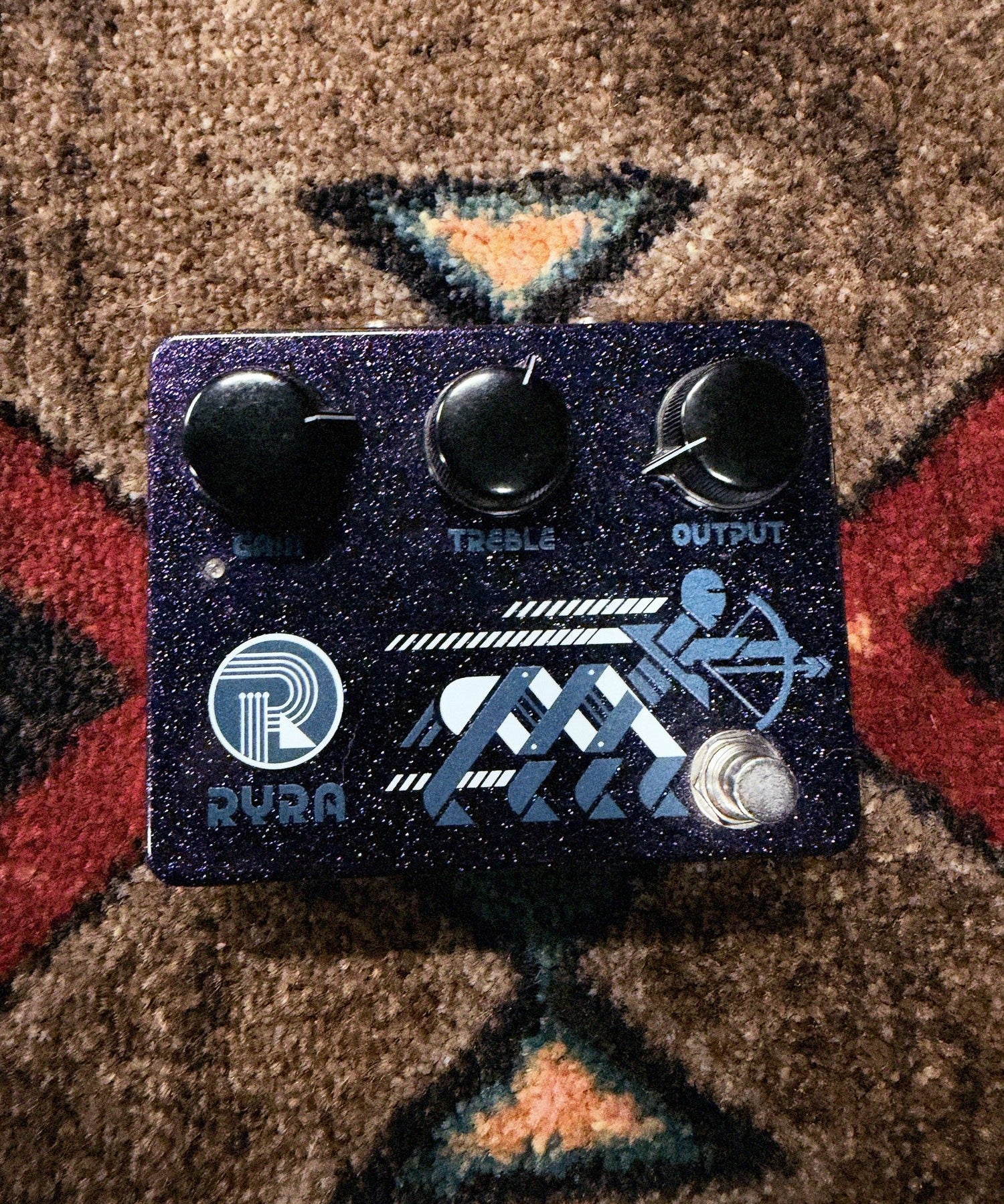 RYRA The Klone, dark blue sparkle: top with the Gain, Treble and Output knobs, the RYRA logo, the archer graphic and the footswitch
