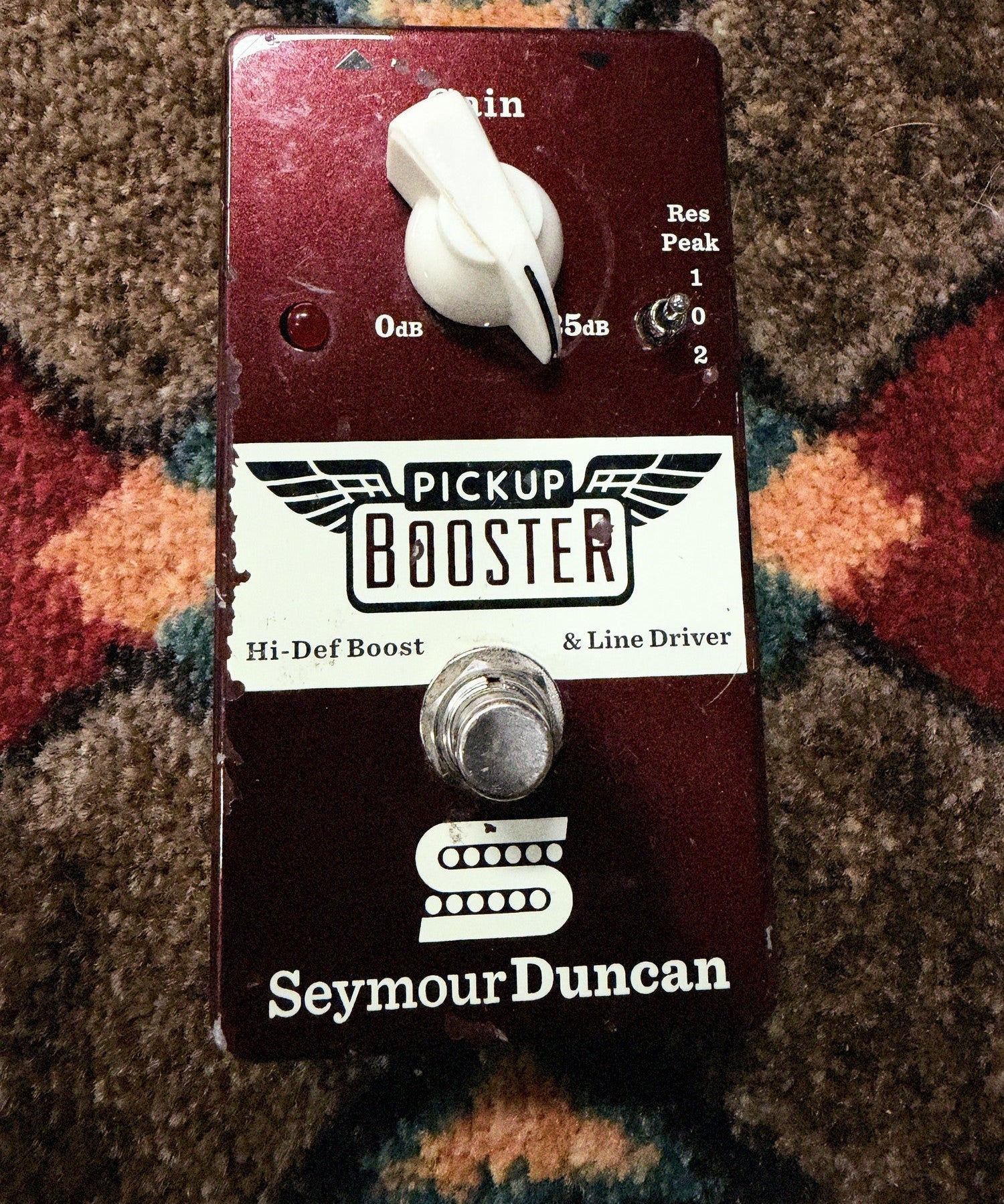 Seymour Duncan Pickup Booster, dark red: top with the Gain knob, the Res Peak switch, the LED and the footswitch, with chips along the left edge