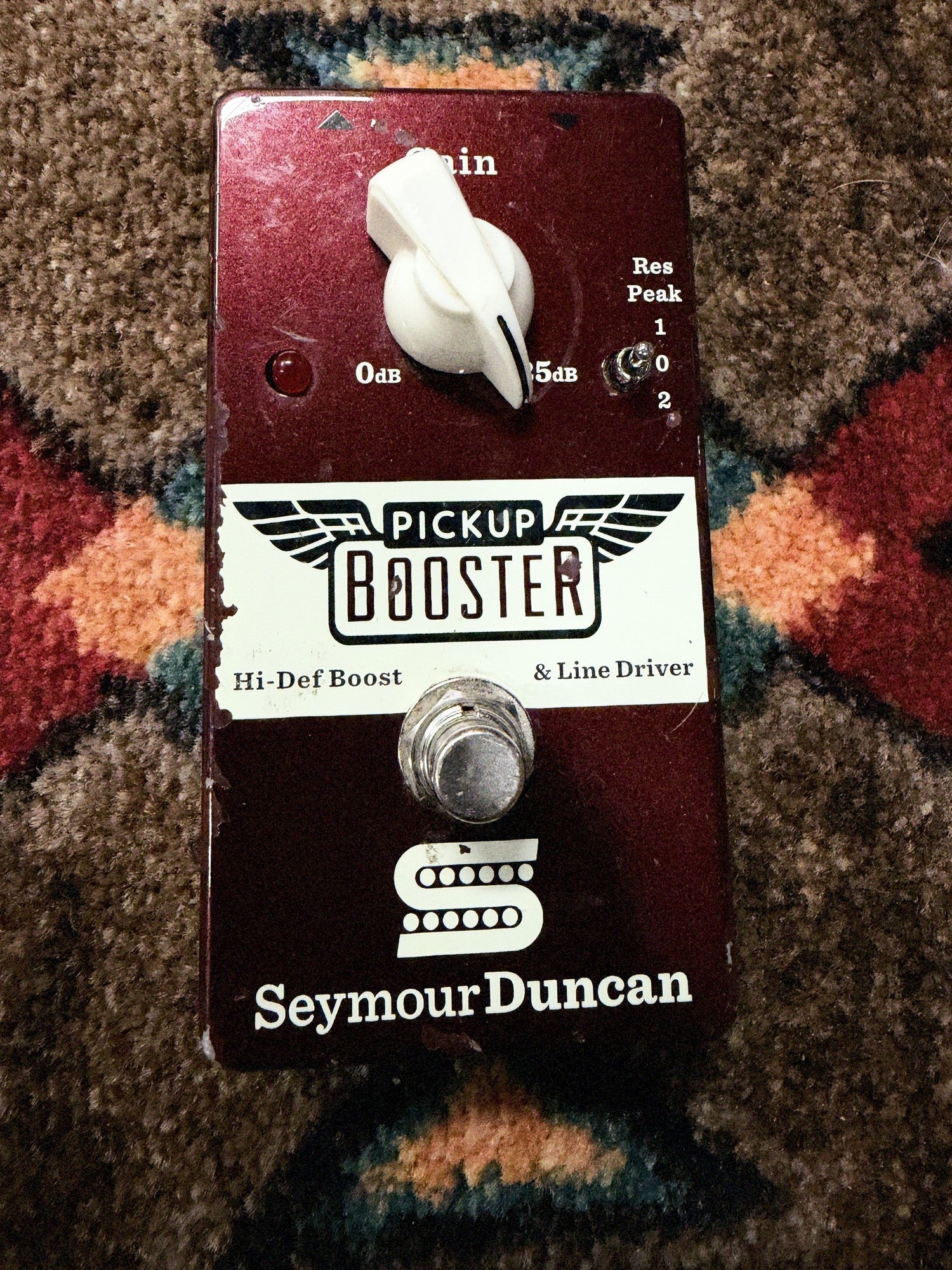 Seymour Duncan Pickup Booster, dark red: top with the Gain knob, the Res Peak switch, the LED and the footswitch, with chips along the left edge