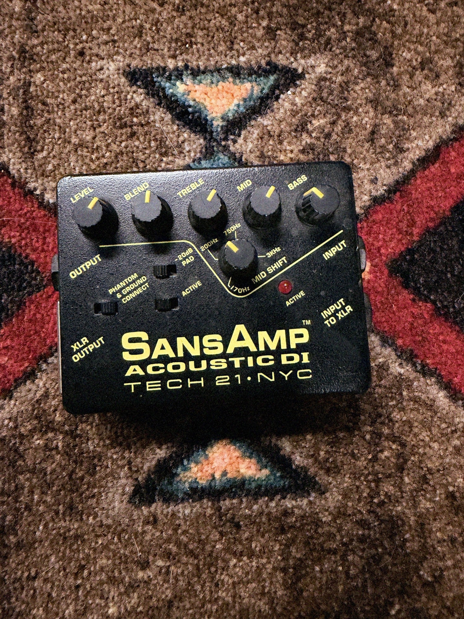 Tech 21 SansAmp Acoustic DI, black: top with the Level, Blend, Treble, Mid, Bass and Mid Shift knobs, the Pad, Phantom and Active switches and the Active LED
