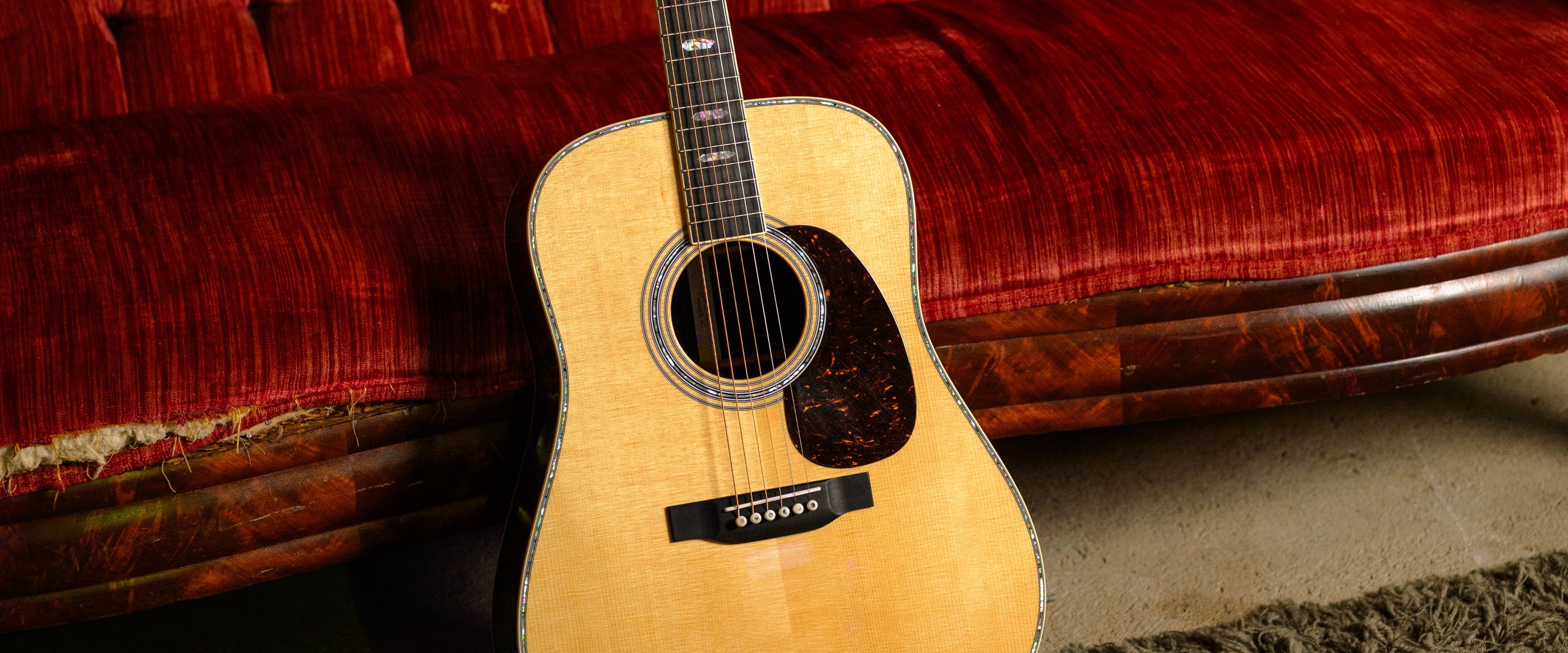 Used guitars and gear at Paul's Guitar Hideout — Martin acoustic on a velvet couch